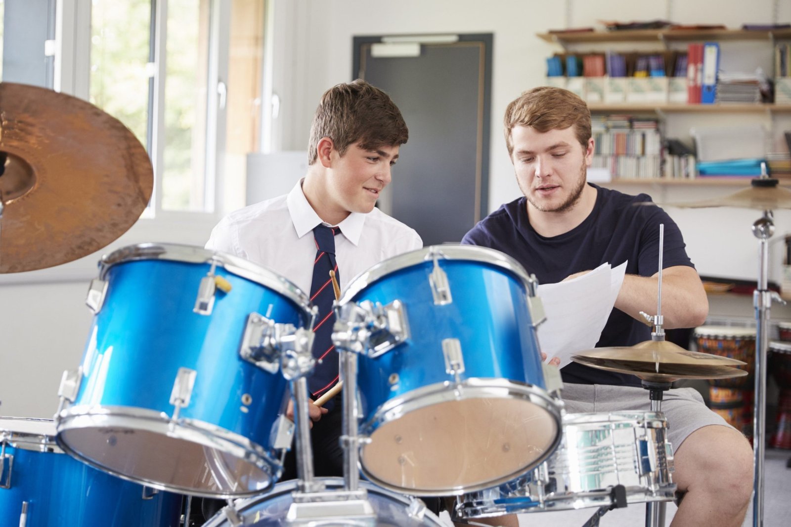male-pupil-with-teacher-playing-drums-in-music-les-2021-08-26-16-13-39-utc.jpg