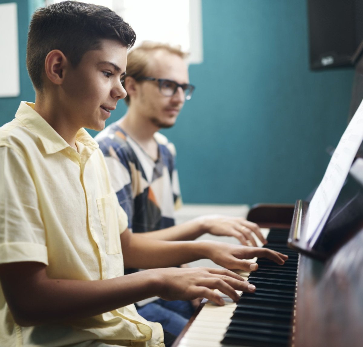 smiling-boy-playing-the-piano-with-his-teacher-2021-09-24-04-29-00-utc.jpg